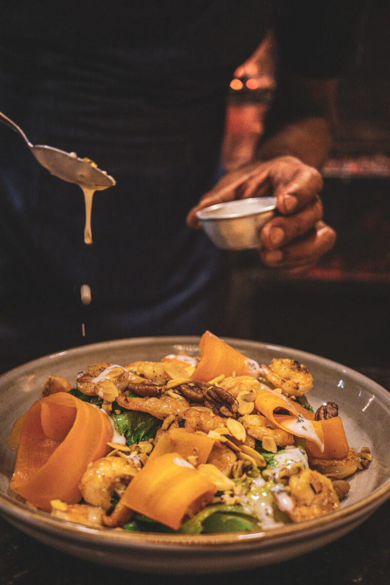 Imagem de um cara servindo um molho em um prato feito no Toro Gramado para simbolizar onde comer em Gramado